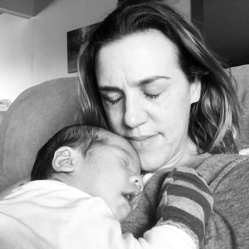 Black and white photo of mother with sleeping baby on her chest