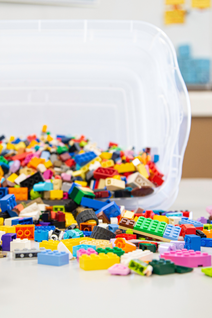 Small plastic bin of multicolored LEGO pieces that can be used to declutter toy collection