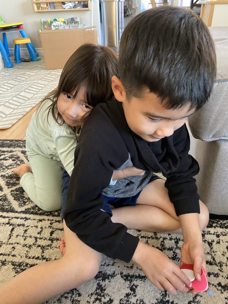 young toddler girl hugging older brother showing the effect of using the Montessori method to strengthen sibling bonds.