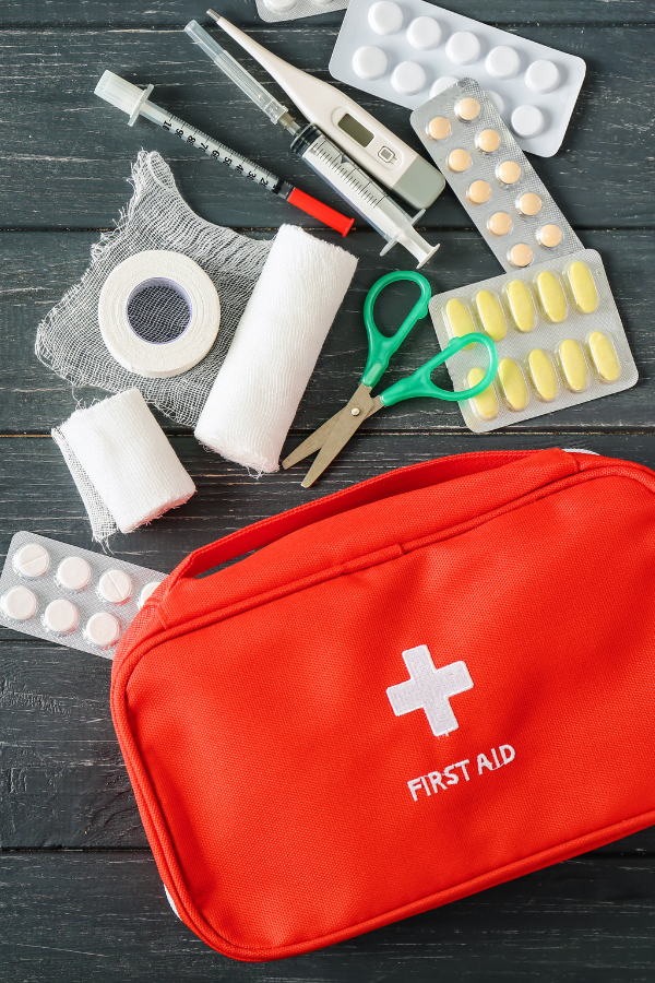 First aid kit with first aid supplies strewn on table showing that teaching kids first aid is important.