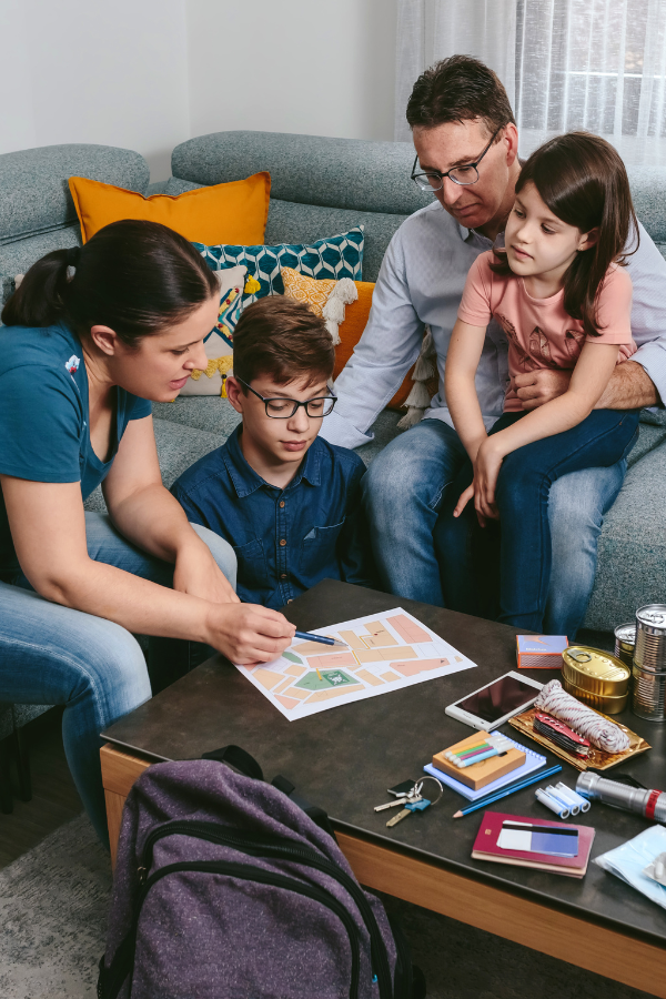 Mother, father and son and daughter gathered around coffee table reviewing an emergency plan.